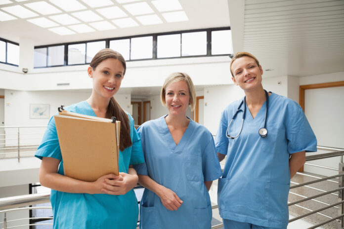 Three smiling nurses in stairwell
