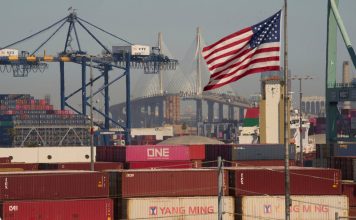 FILE - Containers with Yang Ming Marine Transport Corporation, a Taiwanese container shipping company, are stacked up at the Port of Los Angeles with the the Long Beach International Gateway Bridge seen in the background on Wednesday, April 9, 2025 in Los Angeles. (AP Photo/Damian Dovarganes, File)