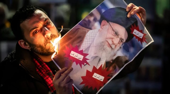 A protester burns an image of the Ayatollah Ali Khamenei with a cigarette during rally in support of the nationwide mass demonstrations in Iran against the government, Tuesday, Jan. 13, 2026 in Zuerich, Switzerland.(Michael Buholzer /Keystone via AP)