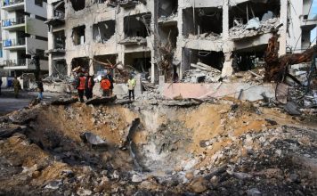 Rescue workers and military personnel survey the scene of a direct hit a day after an Iranian missile struck in Tel Aviv, Israel, Sunday, March 1, 2026. (AP Photo/Oded Balilty)